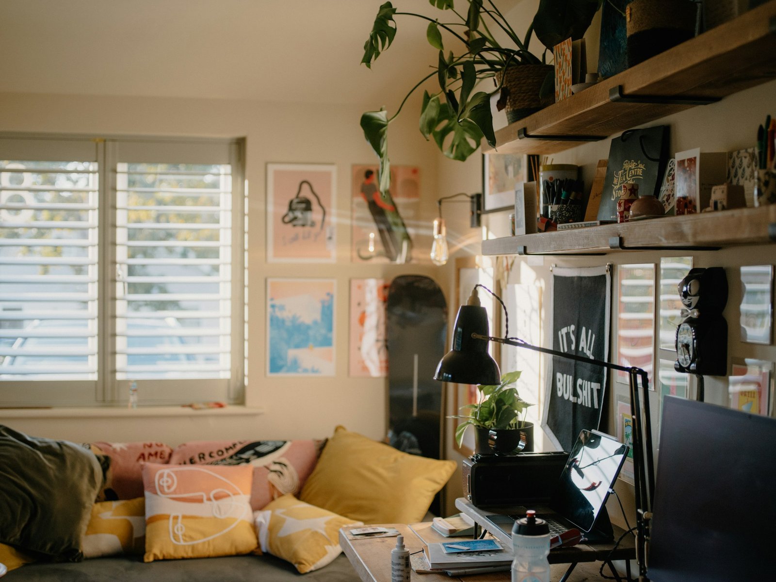 Creative studio corner with desk, shelves, plants, and artwork.